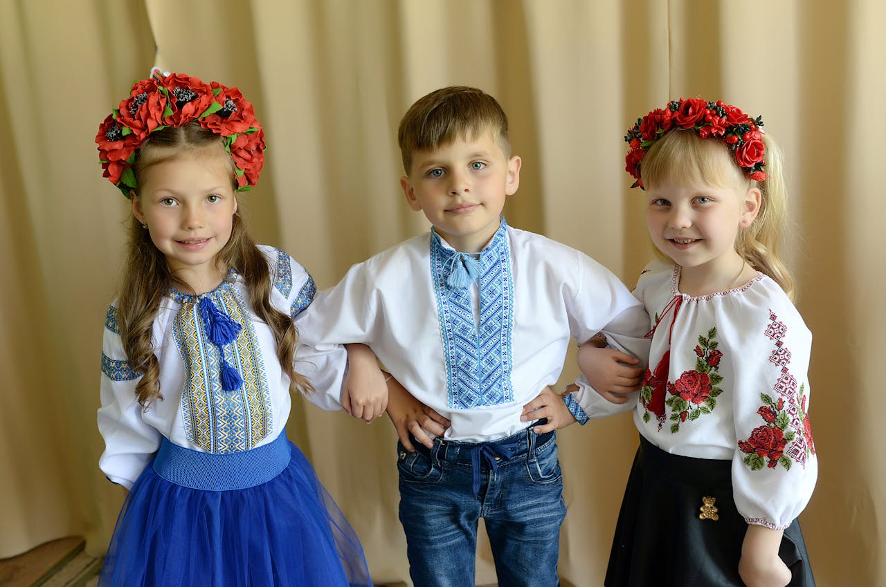 Three children dressed in traditional Ukrainian attire posing indoors.